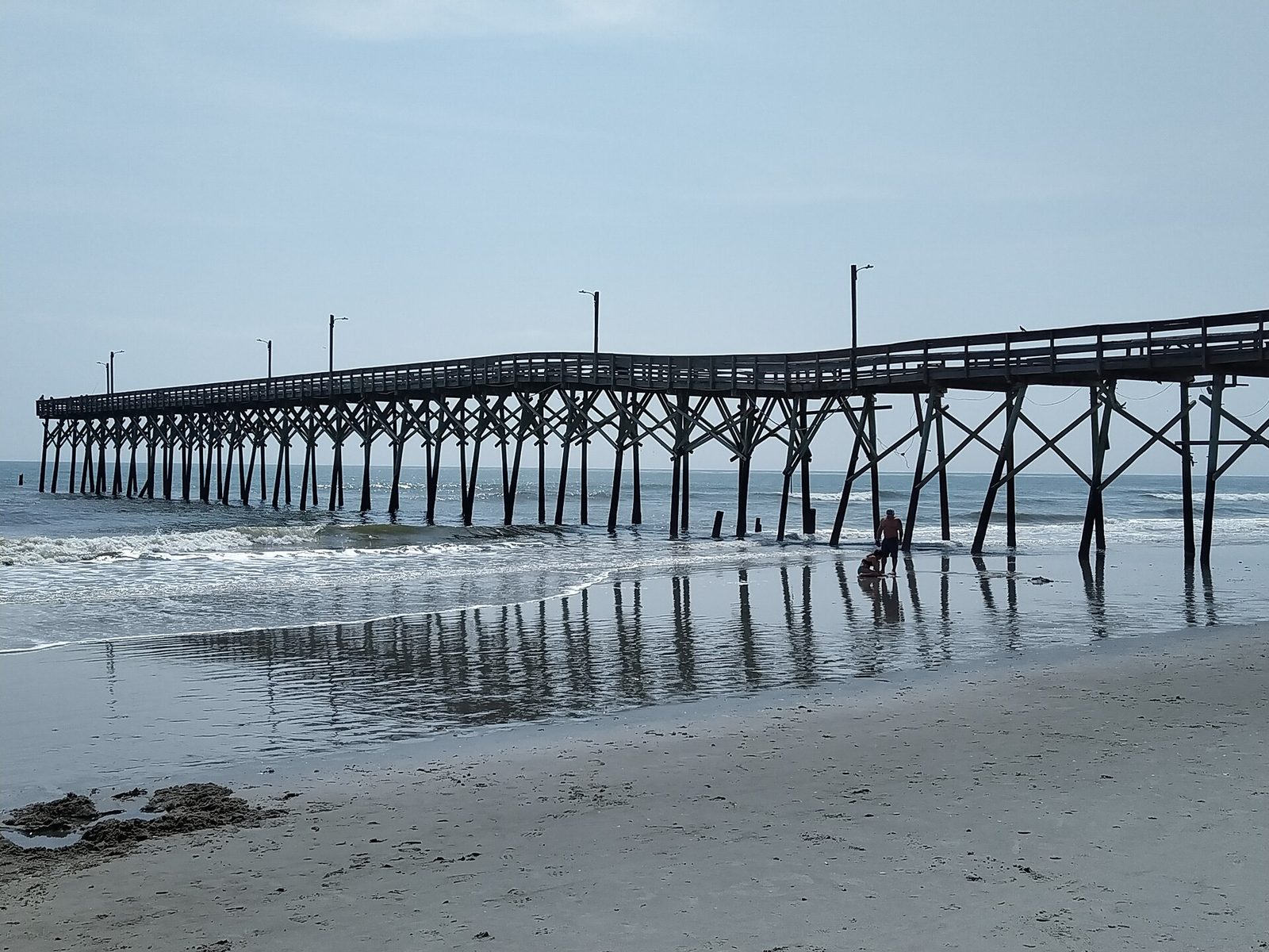 The Holden Beach fishing pier on a grey day, seen from the sand. The pier is now closed.
